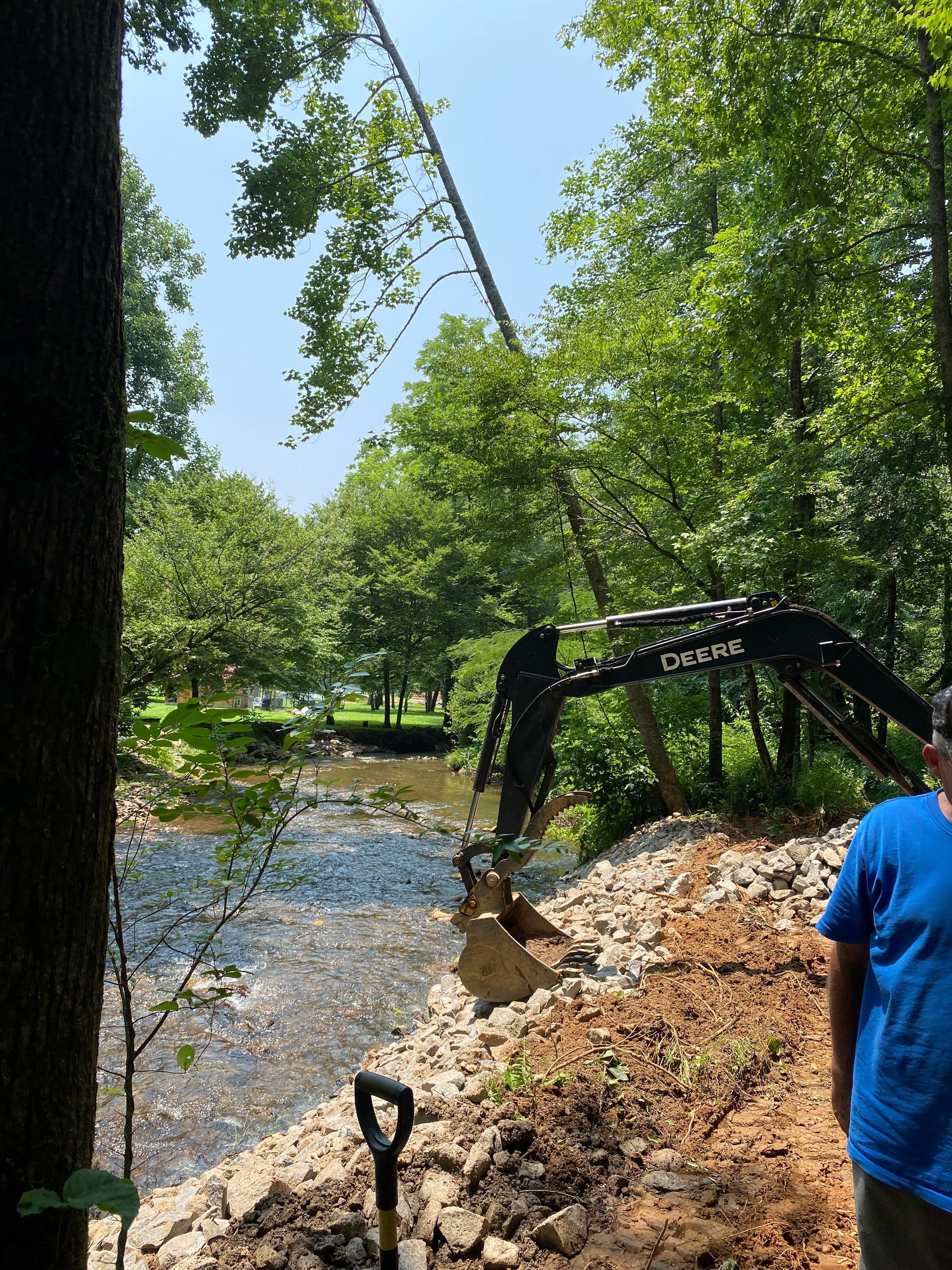 Deere excavator digging stream bank