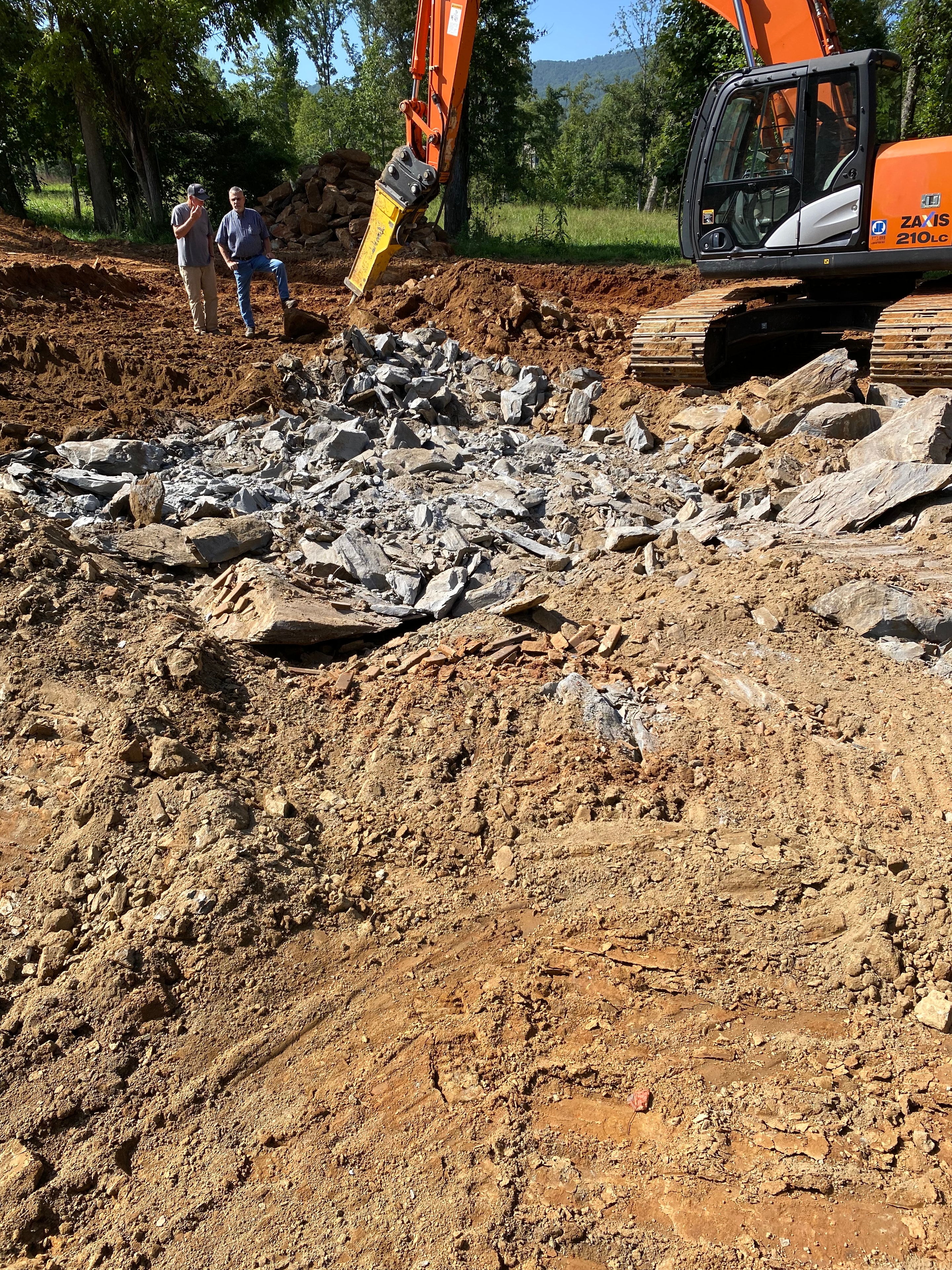 Orange excavator breaking concrete debris