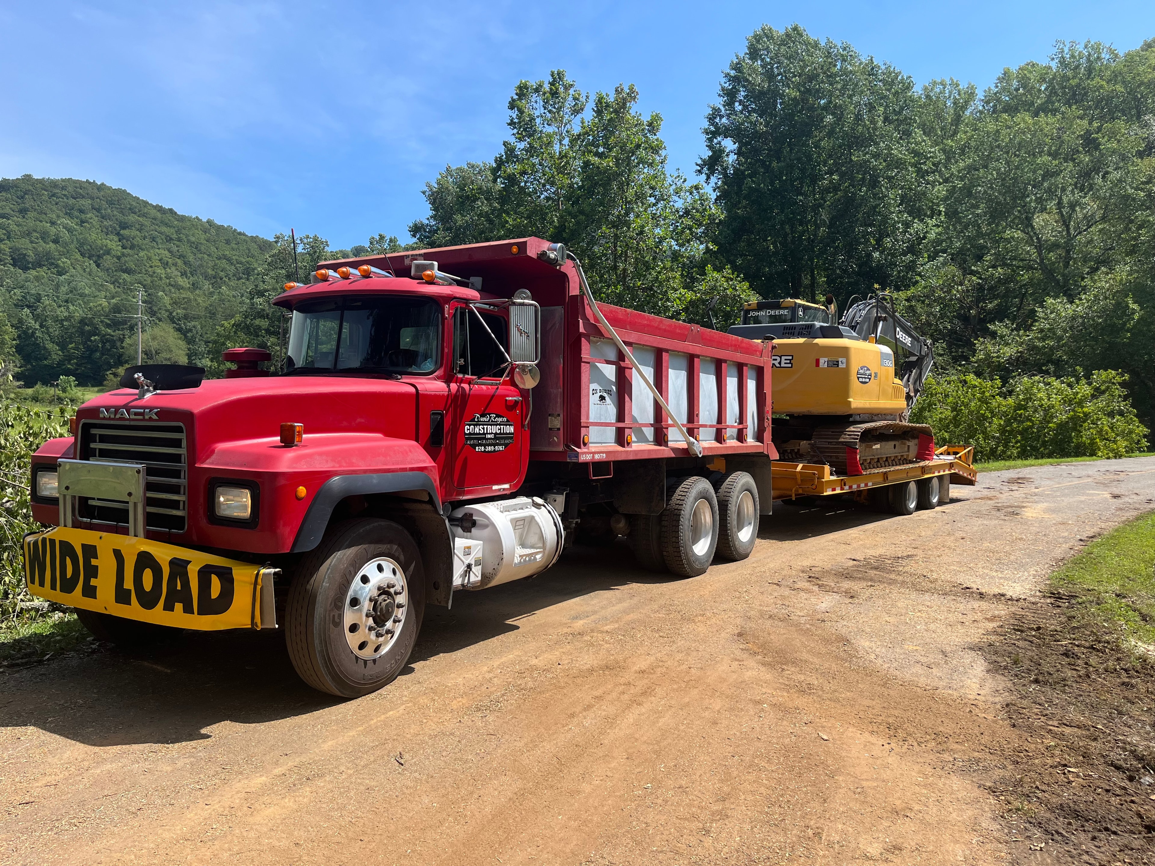 Red Mack dump truck hauling excavator