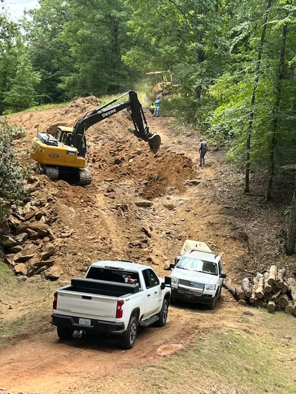 Excavator clearing forest road construction site